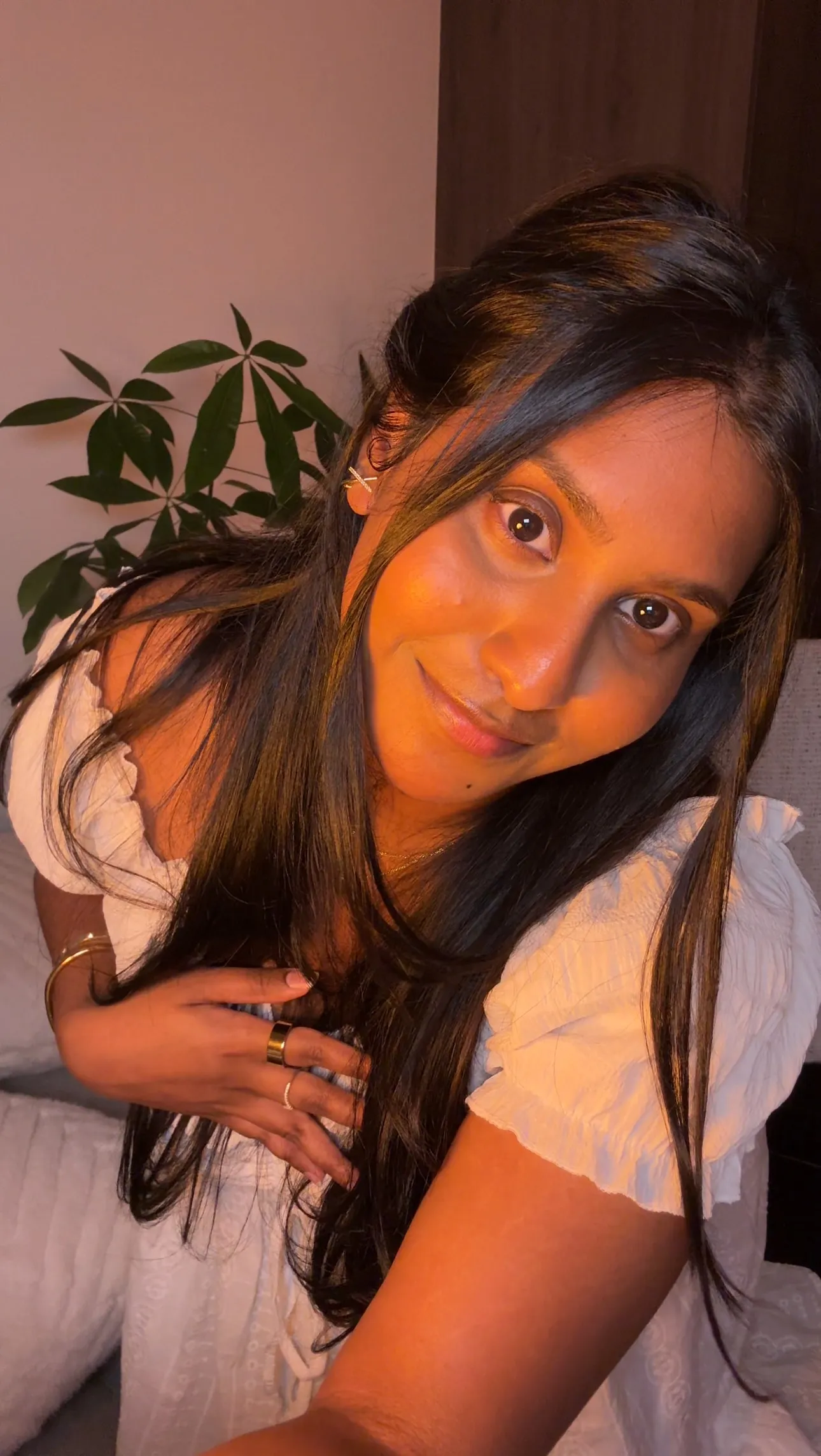 Nina in a white dress, leaning toward the camera with a small smile, in warm evening light